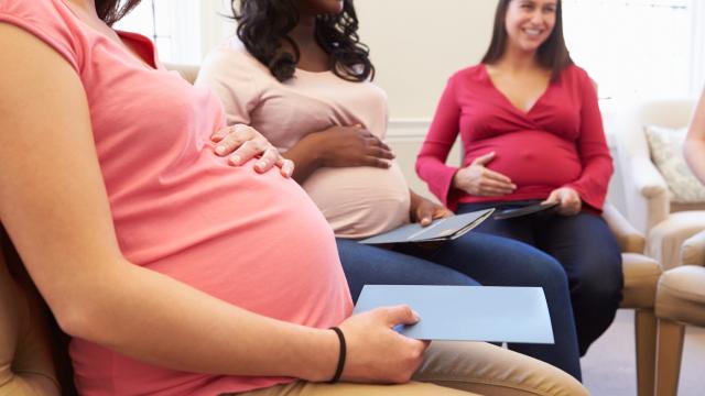 Three pregnant people sit in a circle at a prenatal class