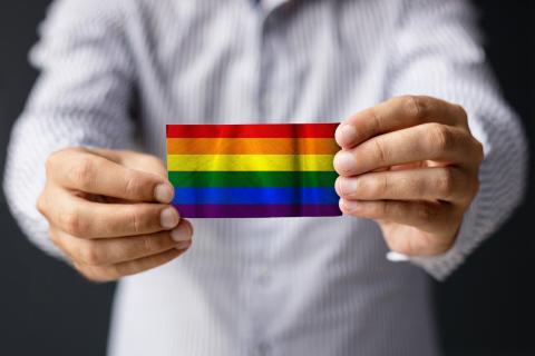 Adult hands holding a small rainbow colored rectangle